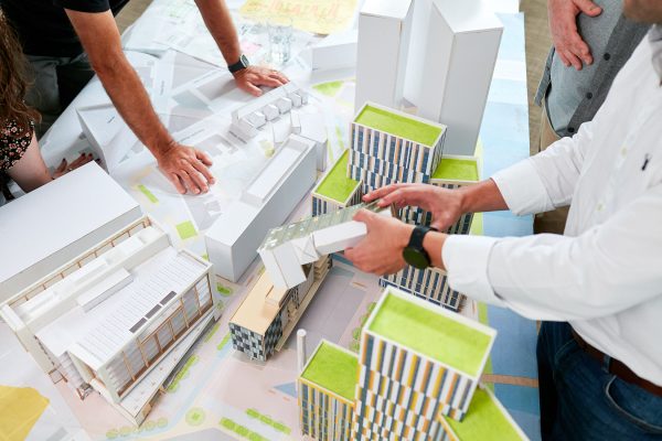 Architects discussing architectural models and masterplan of Cardiff' Central Quay development.